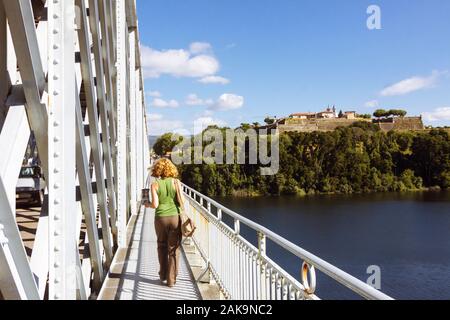 Valenca, Portugal : A young woman walks towards Valença's fortress on the Old international bridge over the Minho river dividing Spain and Portugal. Stock Photo