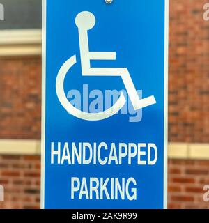 Square Close up of Handicapped Parking sign against blurred red brick wall of church Stock Photo