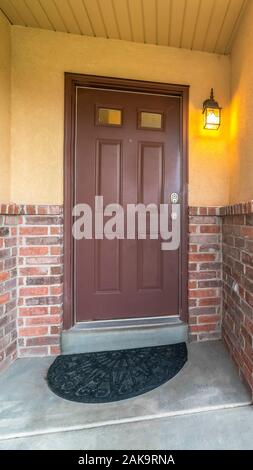 Vertical Brown door with glass panels of a home with concrete and brick exterior wall Stock Photo