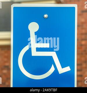 Square frame Close up of Handicapped Parking sign against blurred red brick wall of church Stock Photo