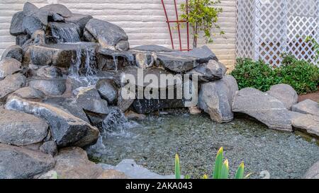 Panorama Artificial stone cascade waterfall in backyard on a sunny day Stock Photo