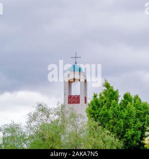 Square Bell Tower of a church rising above green trees Stock Photo