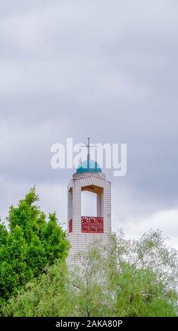 Vertical Bell Tower of a church rising above green trees Stock Photo
