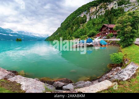 Traditional wood house and boats on the Lake Brienz in swiss village Iseltwald, Switzerland Stock Photo