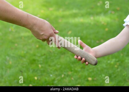 woman giving the relay baton to the next generation into a child's hand Stock Photo