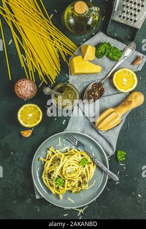 Spaghetti pasta bucatini with pesto sauce and parmesan. Italian traditional perciatelli pasta by genovese pesto sauce in two gray dishes served with w Stock Photo