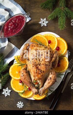 Concept of Christmas or New Year dinner roasted turkey stuffed with rice and Cranberry sauce on wooden table. Top view. Stock Photo