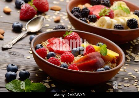 Fruit healthy muesli with peaches strawberry almonds and blackberry in clay dish on wooden kitchen table Stock Photo