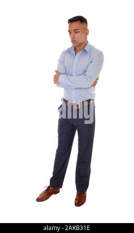 A handsome young east Indian man standing in a blue shirt with his arms crossed, looking down, isolated for white background Stock Photo