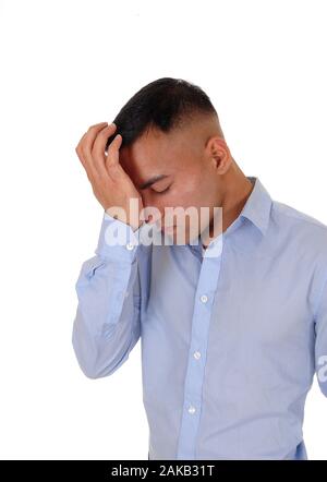 A handsome east Indian business man standing in the studio isolated over white background, in a blue shirt with one hand on his forehead thinking hard Stock Photo