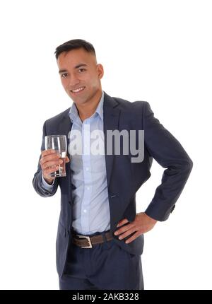 A young east Indian man standing in his suit with a glass of water,  looking into the camera and drinking, isolated for white background Stock Photo