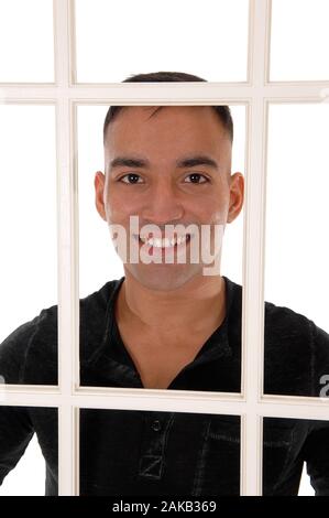 A happy east Indian man standing behind a white window frame in a black dress shirt with a big smile, isolated for white background Stock Photo
