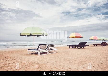 Sunbeds with umbrellas on an empty beach, color toning applied, Sri Lanka. Stock Photo