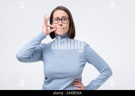 Beautiful caucasian mature woman shutting mouth and lips shut as zip