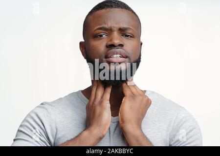 Young afro man suffering from chronic pharyngitis, palping his neck Stock Photo