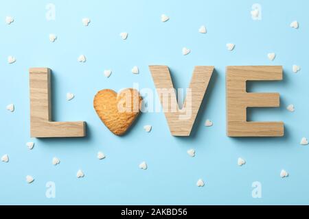 Love made of wooden letters and cookie on blue background, top view Stock Photo