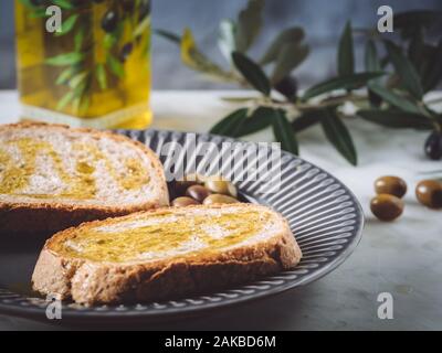 two slices of bread with extra virgin oil. Olives and olive leaves on background. Healthy food, healthy diet, traditional mediterranean product Stock Photo