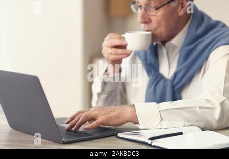 Mature Gentleman Man Working On Laptop Having Coffee Sitting In Modern Office. Selective Focus, Cropped Stock Photo