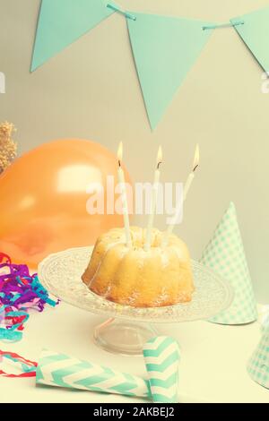 A birthday bundt cake with candles on a crystal cake plate Stock Photo