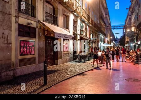 Tourists enjoying evening on a Pink Street in Lisbon with Striptease bar on a foreground. Stock Photo