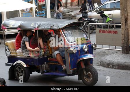 Bangkok, Thailand - December 26, 2019: Three wheeled tuk tuk taxi on a street with many passengers. Stock Photo