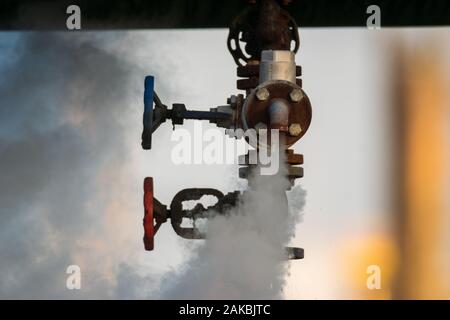 broken valve at the factory hydraulic system, leaking hot liquid and steam under enormous pressure Stock Photo