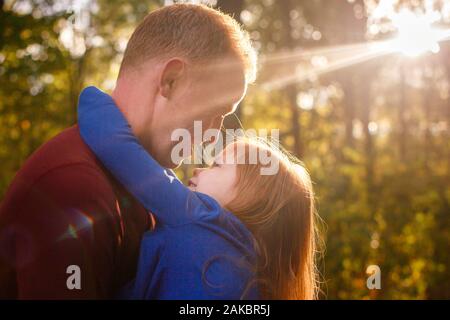 A girl gazes adoringly at her father while being held in his arms Stock Photo