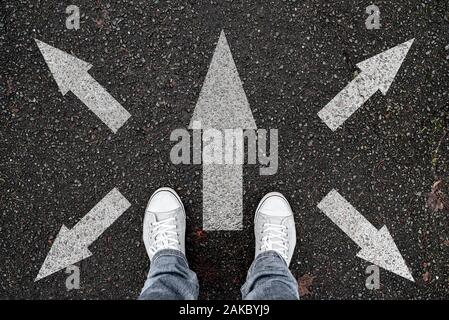 person standing on road with arrow markings pointing in different directions, decision making concept