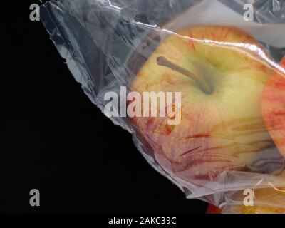 red apple in a plastic pocket isolated on black background with copy space Stock Photo