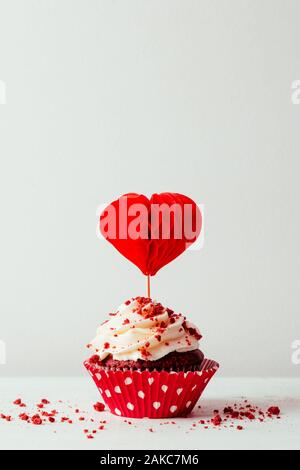 Valentines red velvet cupcake with a red heart shaped cake pick on a white background Stock Photo