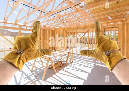 Male Contractor Hands Framing Unfinished House Framing At Construction Site Stock Photo