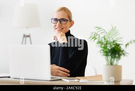 Cheerful teacher working online on pc and smiling to camera, having online class Stock Photo
