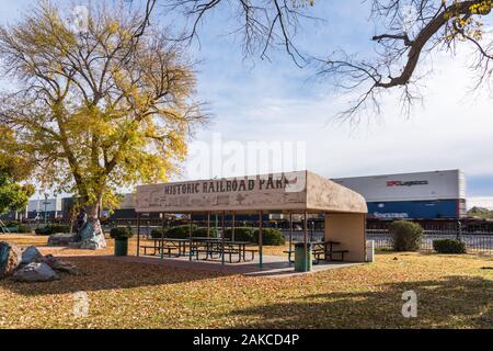 Wilcox, AZ - Nov. 24, 2019: The picnic pavillion in Historic Railroad Park with a train in motion going past on the tracks behind it. Stock Photo