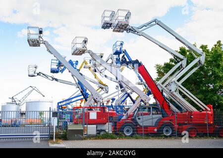Colorful aerial platform cranes, machines and working equipment in industrial area, Frankfurt, Germany Stock Photo