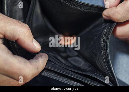 Hand holding black wallet with only one coins .This image signifies the use of money inexorably.The poor man holds a wallet with coins. Stock Photo