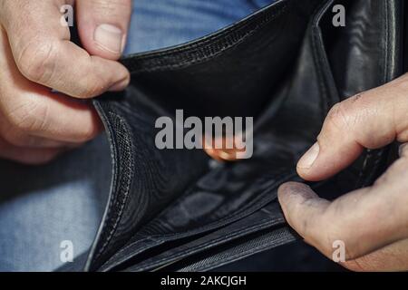 Hand holding black wallet with only one coins .This image signifies the use of money inexorably.The poor man holds a wallet with coins. Only coins rem Stock Photo
