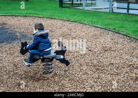 A small boy playing on a rocking ride in the park Stock Photo