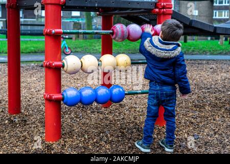 A small boy playing with a giant abacus in a park Stock Photo