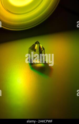 Close up still image of a yellow citrine  crystal illuminated with colorful spotlight on neutral ground. Stock Photo