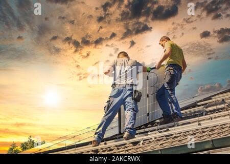 Installing solar photovoltaic panel system. Solar panel technician installing solar panels on roof. Alternative energy ecological concept. Stock Photo