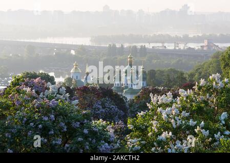 Spring landscape. City of Kiev - capital of Ukraine. Botanical Garden with blossoming lilac bushes. View of the Vydubychi Monastery and the River Dnie Stock Photo