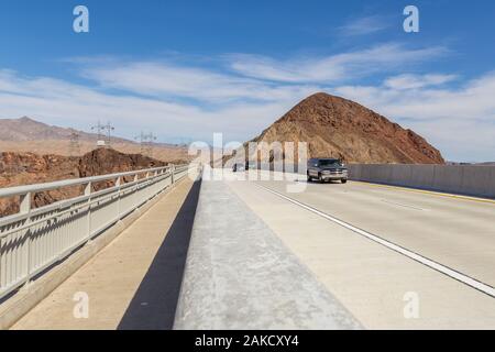 Boulder City, Nevada, USA- 01 June 2015: Cars on the highway over Hoover Dam on the Colorado River. High voltage poles and hills in the background. Stock Photo