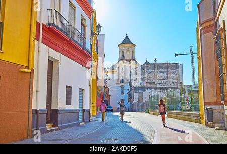 Watch the streetscape of Calle Parras in old town with a view on tall medieval bell tower of San Felipe Neri Church, Malaga, Spain Stock Photo