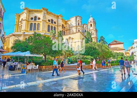 MALAGA, SPAIN - SEPTEMBER 26, 2019: The medieval stone basilica of Malaga Cathedral with lush green topiary garden on the foreground, on September 26 Stock Photo