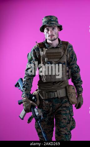 american  marine corps special operations modern warfare soldier with fire arm weapon and protective army tactical gear ready for battle on pink backg Stock Photo