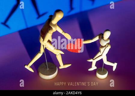 Two wooden men hold their hearts in their hands. On a blue background. Stock Photo