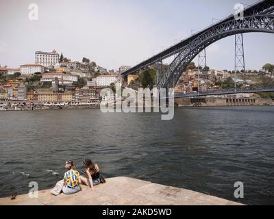 Two young women enjoying the view of Porto on the Douro riverbank looking north. Stock Photo
