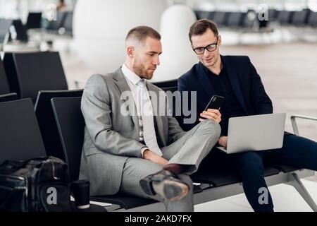 Business colleagues waiting at airport lounge sitting and talking. Stock Photo