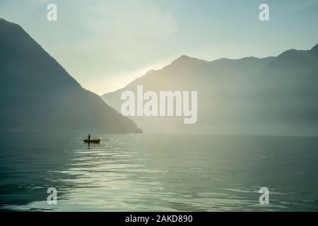 Fisher on lake Como in boat. Mountains  on background. Christmas holiday Stock Photo