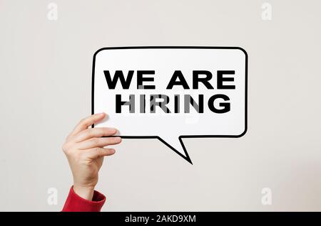 We are hiring text on speech balloon held by hand on light background. Recruitment, human resources and employment concept. Stock Photo